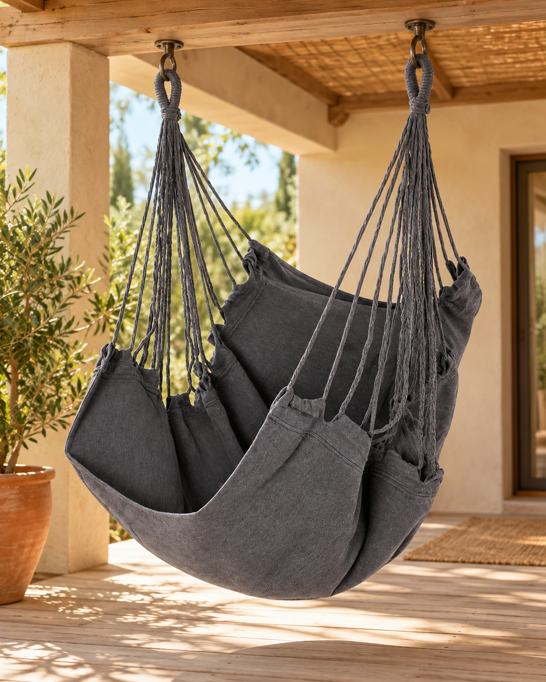 Chaise hamac en toile grise suspendue sous une véranda Image