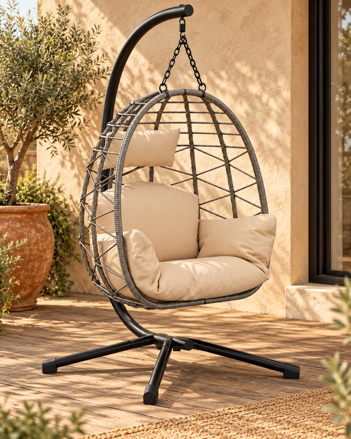 Fauteuil suspendu gris à coussins beige sur pied noir, sur une terrasse Image