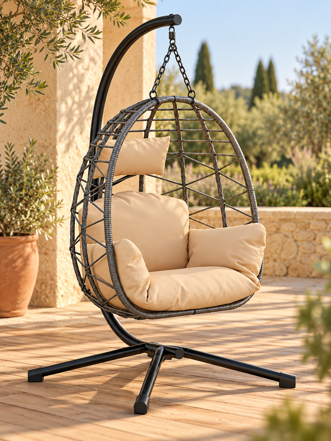 Fauteuil suspendu tressé gris avec coussins beiges et pied noir, dans un jardin méditerranéen. Image