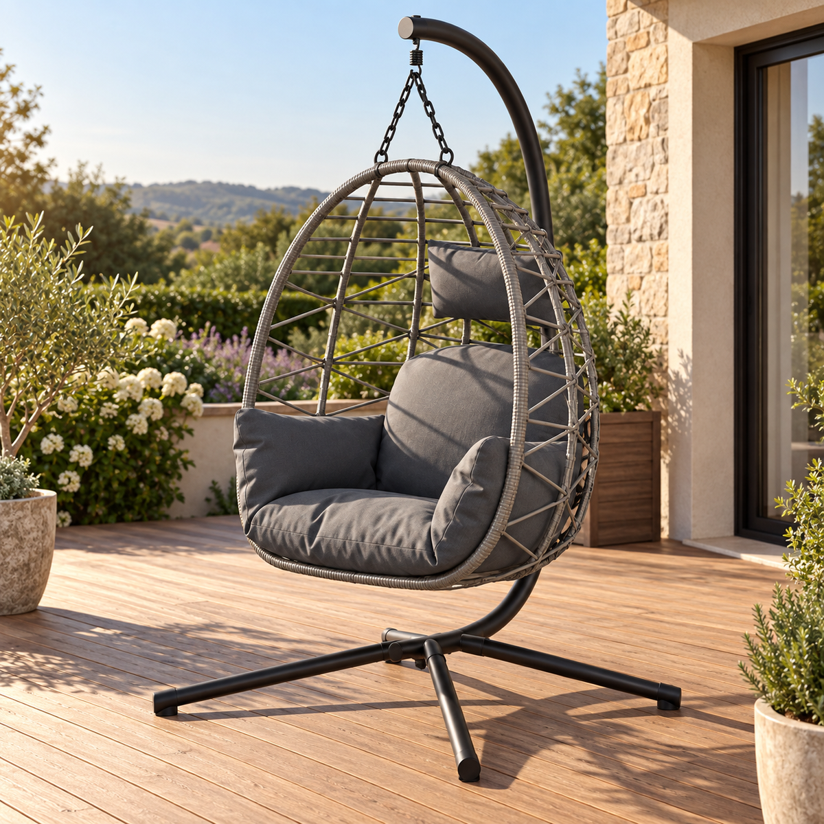 Fauteuil suspendu gris à coussins anthracite, vue de trois quarts sur une terrasse