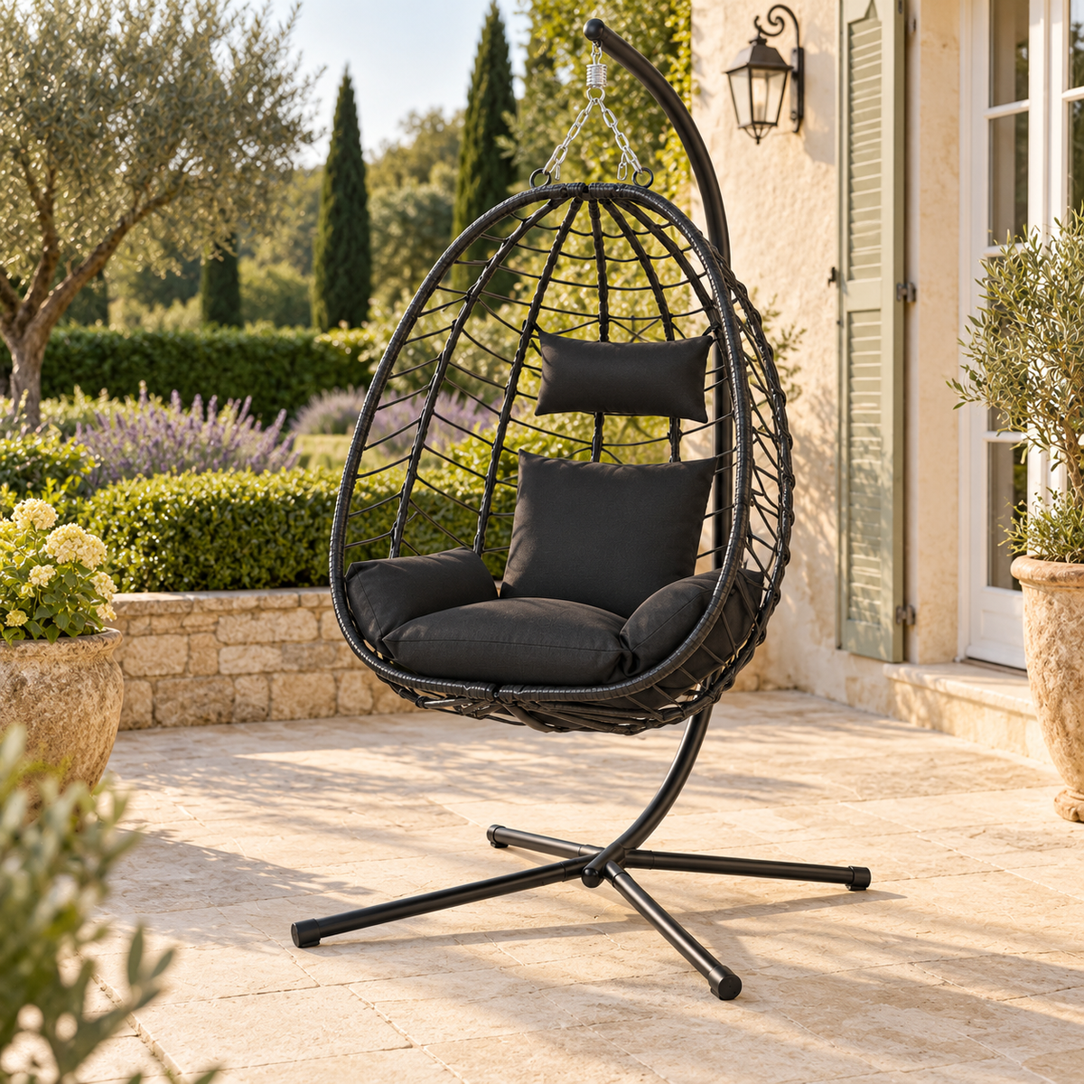 Fauteuil œuf noir avec coussins anthracite et pied, vue de trois quarts en terrasse