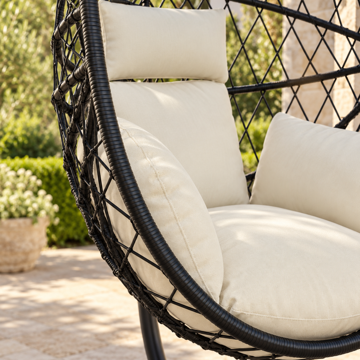 Détail des matières et des coussins de la fauteuil œuf sur pied en rotin foncé avec coussins crème