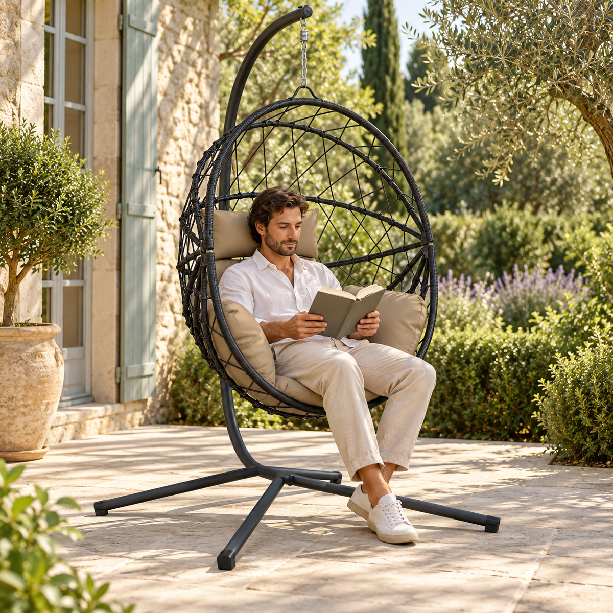 Fauteuil œuf sur pied en rotin foncé avec coussins taupe utilisée sur une terrasse couverte