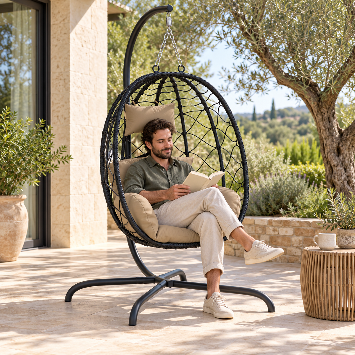 Fauteuil œuf noir sur pied avec coussins taupe avec une personne sur une terrasse