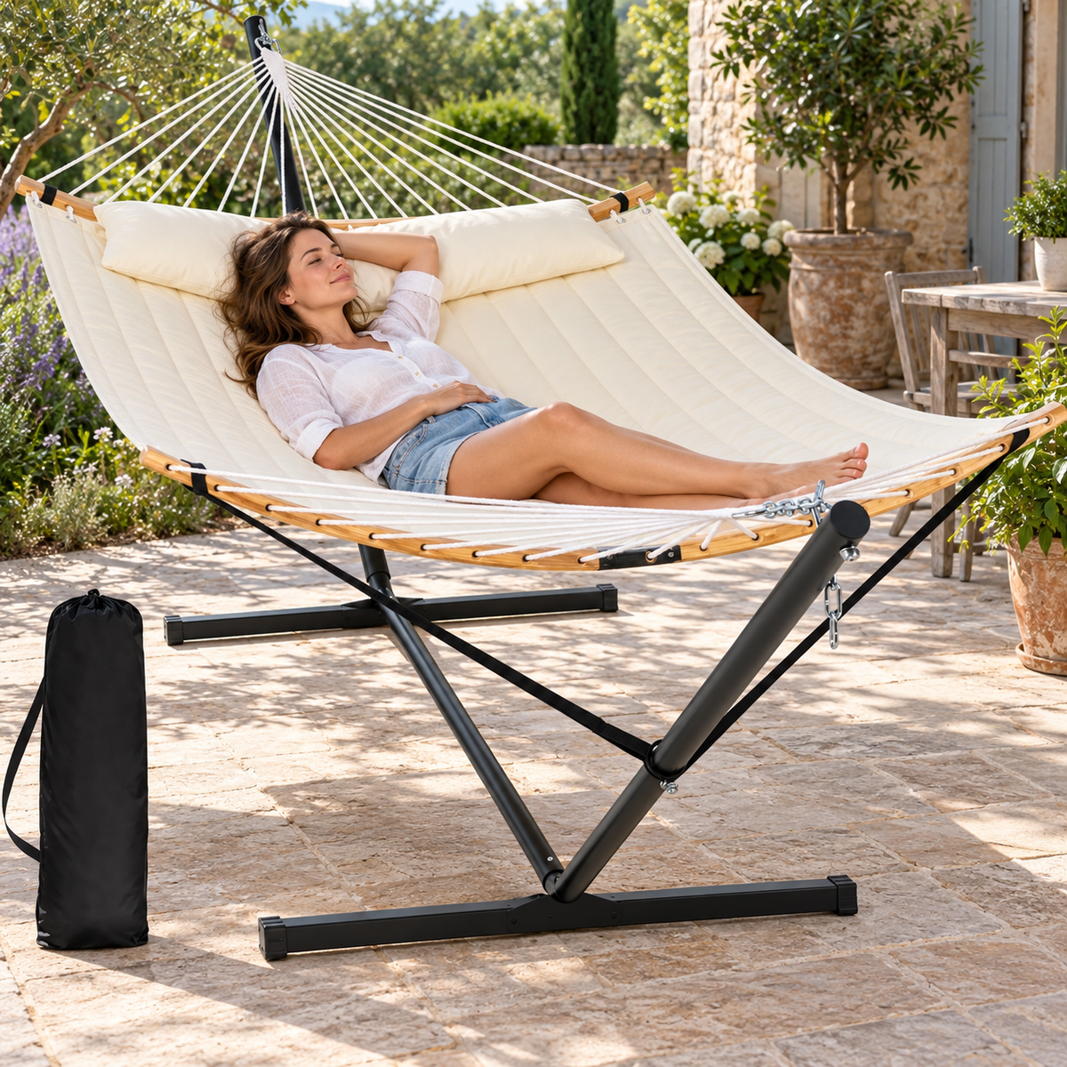 Hamac matelassé blanc cassé avec support acier utilisé par une personne dans un jardin