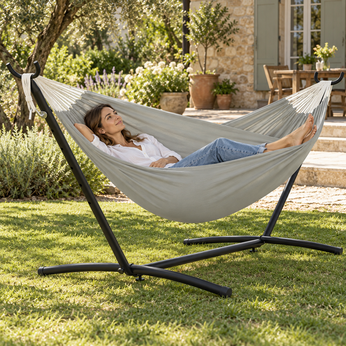 Hamac gris avec support acier noir utilisé par une personne dans un jardin