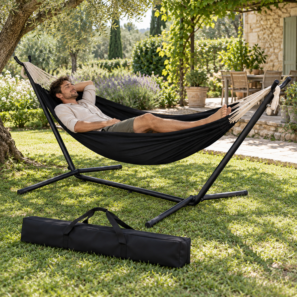 Hamac anthracite avec support noir et sac utilisé par une personne dans un jardin