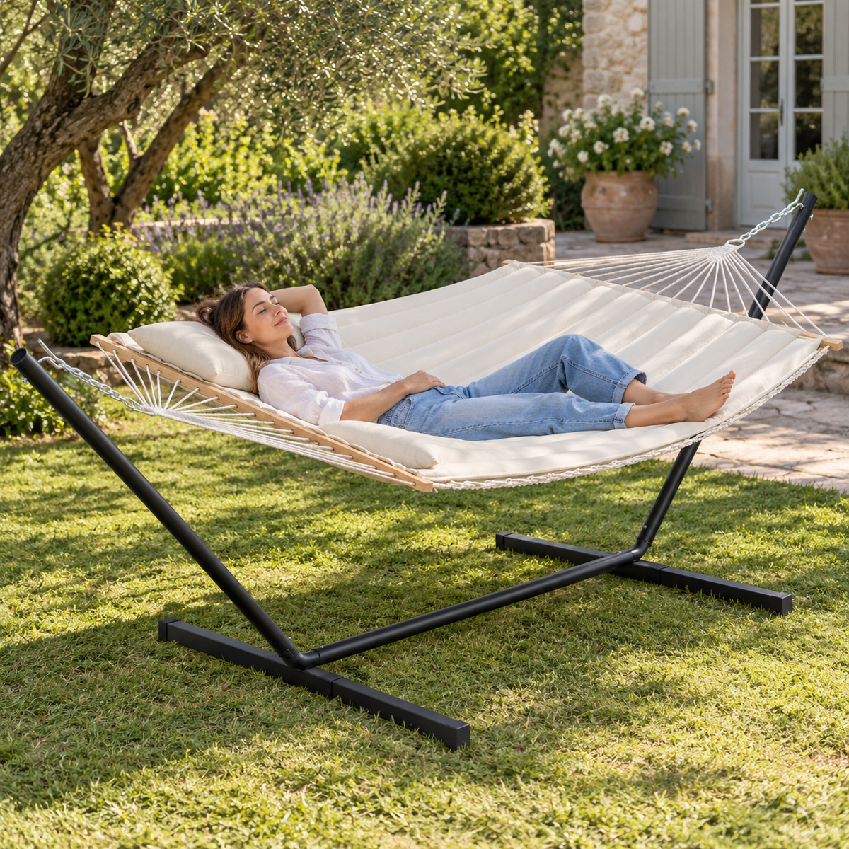 Hamac en corde beige uni avec matelas et support acier en utilisation dans un jardin ou sur une terrasse
